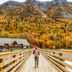 Hiker walking towards mountain of fall foliage in Quebec National Park