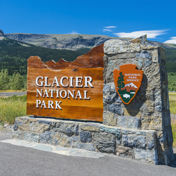 Glacier National Park entrance sign with Park scenery