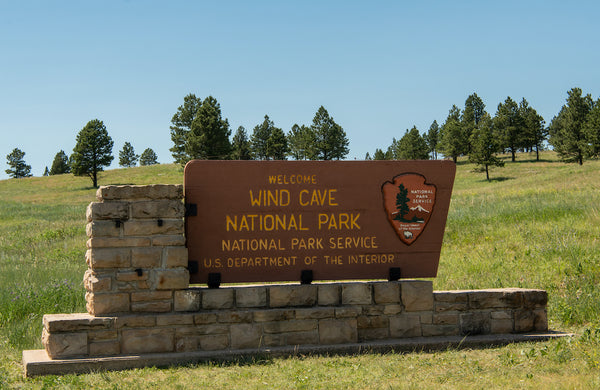 Wind Cave National Park Welcome Sign in Grassy Field on Sunny Day
